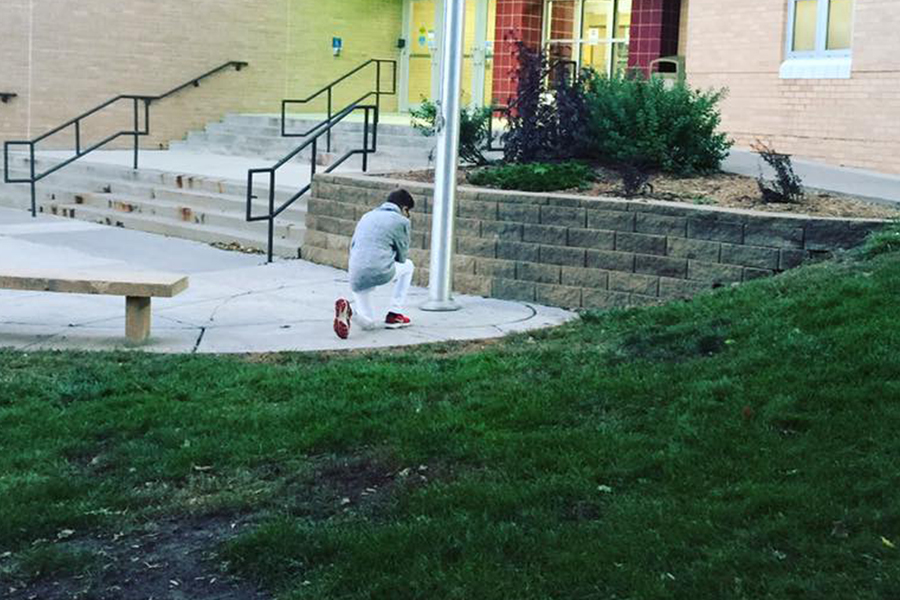 A photo of a single student praying alone, at his school's flagpole